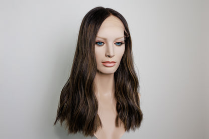 A shoulder-length wavy wig with dark brown roots and lighter caramel-brown highlights, displayed on a mannequin head against a plain light gray background.